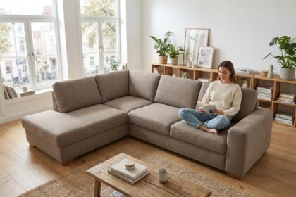 Femme lisant sur un canapé d'angle taupe dans un salon scandinave lumineux et bien aménagé
