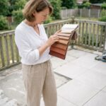 Femme planifiant le choix d'un store avant la rénovation de sa terrasse en consultant des échantillons de tissu