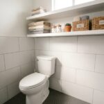 Rangements malins au-dessus des toilettes avec étagères flottantes, paniers en osier et serviettes pliées dans une salle de bain moderne