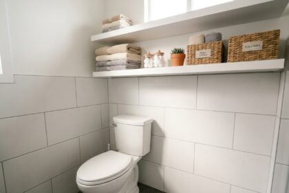 Rangements malins au-dessus des toilettes avec étagères flottantes, paniers en osier et serviettes pliées dans une salle de bain moderne