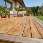Terrasse en bois exotique teck avec mobilier de jardin et plantes vertes dans un jardin résidentiel